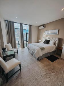 ein großes Schlafzimmer mit einem großen Bett und einem Stuhl in der Unterkunft Suites Lassa in Ensenada