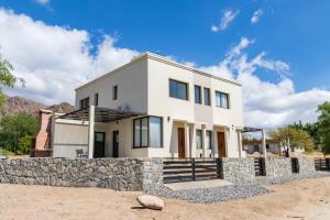 ein weißes Haus mit einer Steinmauer in der Unterkunft Refugio Vertientes in Cafayate
