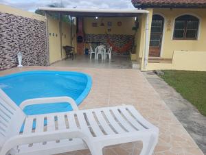 - une piscine avec un banc blanc à côté d'une maison dans l'établissement Bella casa de praia, à Araruama