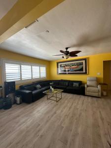een woonkamer met een bank en een plafondventilator bij Yellow Cactus Oasis in White Water