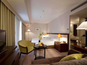 a hotel room with a bed and a living room at The Cypress Mercure Hotel Nagoya in Nagoya