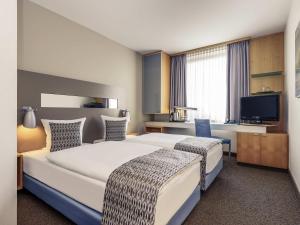 a hotel room with two beds and a television at Mercure Hotel Düsseldorf City Nord in Düsseldorf +82 photos