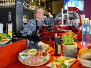 a woman behind the counter of a bar with food at Mercure Hotel Berlin City in Berlin