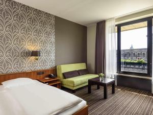 a hotel room with a bed and a chair and a window at Mercure Hotel Trier Porta Nigra in Trier