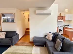 a living room with two couches and a kitchen at Beach Life in Torquay