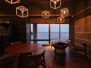a restaurant with tables and chairs and a view of the ocean at IZU RETREAT by Onko Chishin in Higashiizu