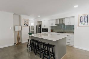 eine Küche mit weißen Schränken und eine Insel mit Barhockern in der Unterkunft Sundrift - Sophisticated Beachside Retreat with Pool in Dunsborough
