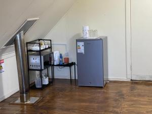 a small refrigerator in a room with a wooden floor at Alojamiento 2 Oriente in Curacautín