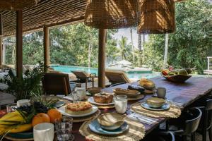 a table with food on it with a pool in the background at Villa 21 in Itacaré