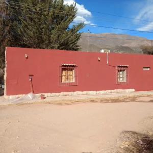 a red house with two windows on the side of it at Casa de campo Villa El Perchel in Huacalera