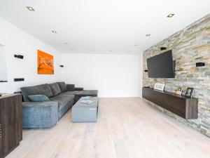 a living room with a couch and a tv on a brick wall at Alpin Chalet ARTE in Söll