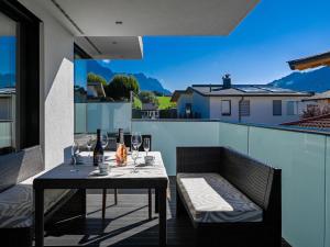 a table and chairs on a balcony with a view of a house at Alpin Chalet ARTE in Söll