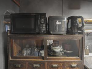 a microwave sitting on top of a cabinet with dishes at 旅館 なおみ in Toba