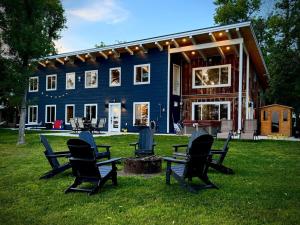 a blue house with chairs sitting in the grass at Designer Lake Cabin- HotTub, Sauna & Massage Chair in Ottertail
