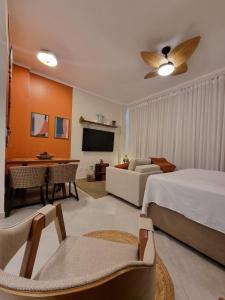 a bedroom with a bed and a couch and a tv at AptoVistamarArtachoJuradoComRoupaCamaBanho in Santos
