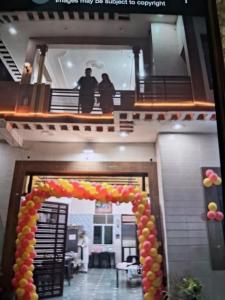 two people standing on the second floor of a building with a balloon arch at Veddaya Farm in Ghaziabad