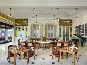 a restaurant with tables and chairs and a piano at The Phoenix Hotel Yogyakarta - Handwritten Collection in Yogyakarta