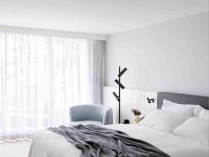 a bedroom with a bed and a chair and a window at Manly Pacific Sydney MGallery Collection in Sydney