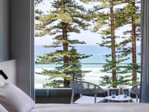 a bedroom with a view of trees and the ocean at Manly Pacific Sydney MGallery Collection in Sydney