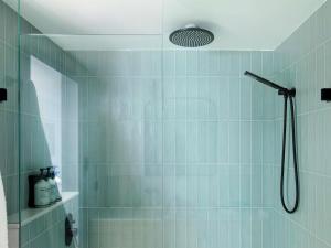 a bathroom with a shower with blue tiles at Manly Pacific Sydney MGallery Collection in Sydney