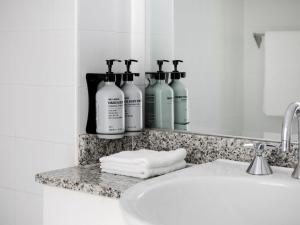 a bathroom counter with three bottles of soap and a sink at Manly Pacific Sydney MGallery Collection in Sydney