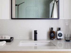 a bathroom sink with a bottle of soap and a mirror at Manly Pacific Sydney MGallery Collection in Sydney +166 photos