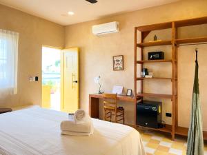 a bedroom with a bed and a desk with a towel at Kuka y Letras in Mérida