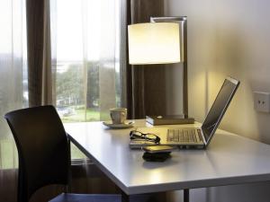 un computer portatile seduto su una scrivania con lampada di Novotel Sydney International Airport a Sydney