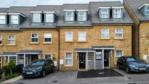 达特福德NEW! 5BR Gem by Prime Vault Properties, Town Centre Near Train Station with Driveway Parking的两辆汽车停在砖楼前