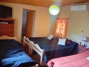 a bedroom with two beds and a tv and a window at Casa de campo Villa El Perchel in Huacalera