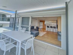 ein Esszimmer und ein Wohnzimmer mit Tisch und Stühlen in der Unterkunft Modern 4-Bed Townhouse with Water Views in Malua Bay