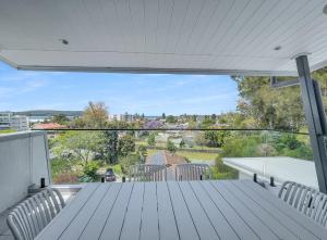 eine weiße Terrasse mit einem Tisch und Stühlen auf einem Balkon in der Unterkunft Modern 4-Bed Townhouse with Water Views in Malua Bay