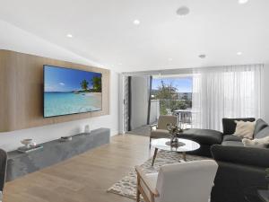 ein Wohnzimmer mit einem Sofa und einem Fernseher an der Wand in der Unterkunft Modern 4-Bed Townhouse with Water Views in Malua Bay + 25 Fotos