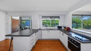 a kitchen with white cabinets and a black counter top at Copa Beach House - Family in Copacabana +7 photos