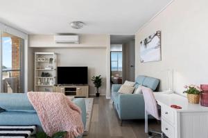 un salon avec un canapé bleu et une télévision dans l'établissement Bright Beachside Escape at The Entrance, à Entrance