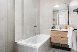 une salle de bain blanche avec une baignoire et un lavabo dans l'établissement Bright Beachside Escape at The Entrance, à Entrance 30 autres photos