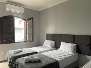 a bedroom with two beds and a window at Pousada Areia in Saquarema