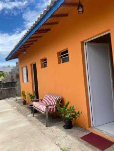 an orange house with a bench in front of it at Flor da Ilha in Estação Quitaúna