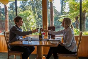 un homme et une femme assis à une table avec des verres à vin dans l'établissement Wilderness Lodge Lake Moeraki, à Haast 20 autres photos