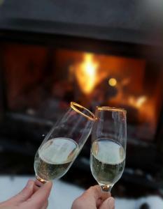 two people holding wine glasses in front of a fireplace at Yourte Voyageuse in Charette