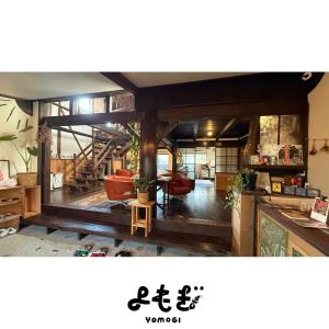 una sala de estar con suelo de madera y una habitación con sillas en YOMOGI GUESTHOUSE, en Tokoname