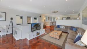 a living room with a couch and a flat screen tv at The Point On Cliff - Two Levels and Views in Avoca Beach