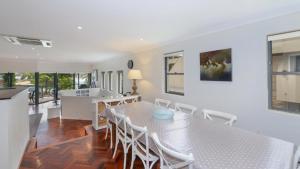 a dining room with a white table and chairs at The Point On Cliff - Two Levels and Views in Avoca Beach