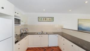 a kitchen with white cabinets and a sink at The Point On Cliff - Two Levels and Views in Avoca Beach