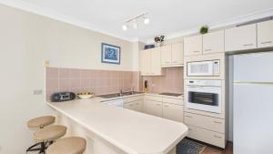 a kitchen with white cabinets and a white counter top at Sandpiper 4 - Great Location in Avoca Beach