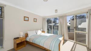 a bedroom with a bed and a large window at Sandpiper 4 - Great Location in Avoca Beach +6 photos