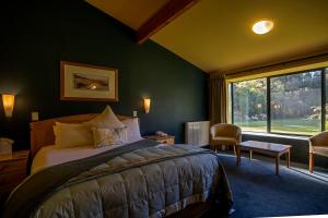 une chambre avec un lit et une grande fenêtre dans l'établissement Wilderness Lodge Lake Moeraki, à Haast
