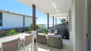 a balcony with chairs and tables on a building at Ocean Sunrise - Magical in Avoca Beach