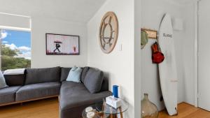 a living room with a couch and a surfboard on the wall at Seaview 5 - Great Beach Views in Avoca Beach