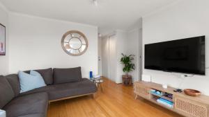 a living room with a couch and a flat screen tv at Seaview 5 - Great Beach Views in Avoca Beach